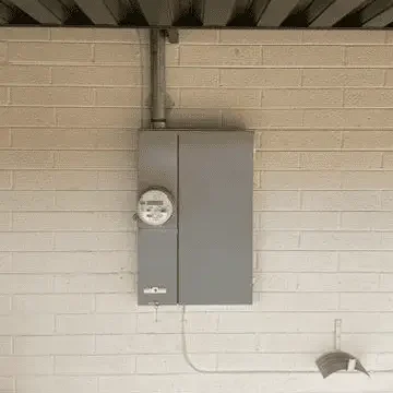 Electrical meter box mounted on a beige brick wall under a metal roof.